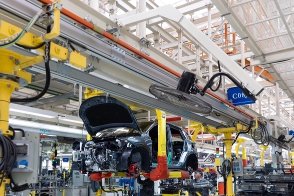 A high-tech automotive assembly line in a modern factory, where every stage of car body production relies on a precision photoelectric sensor.