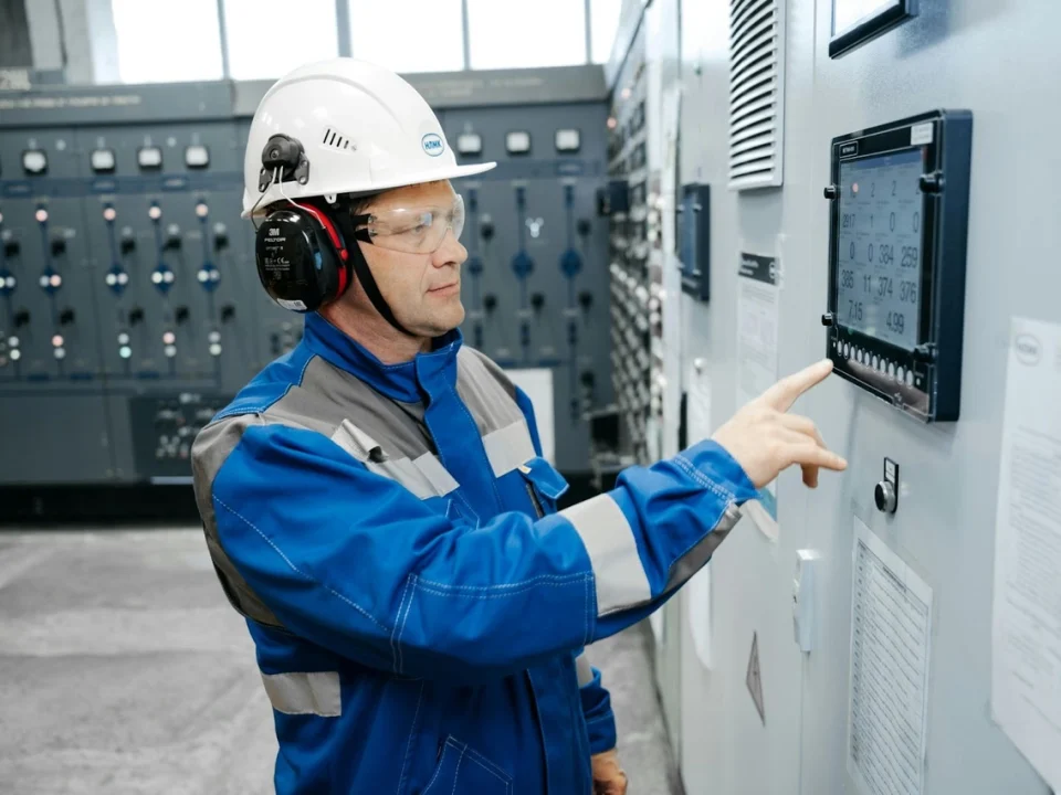 A professional engineer operating a modular PLC system with integrated touchscreen control in an industrial power distribution cabinet.